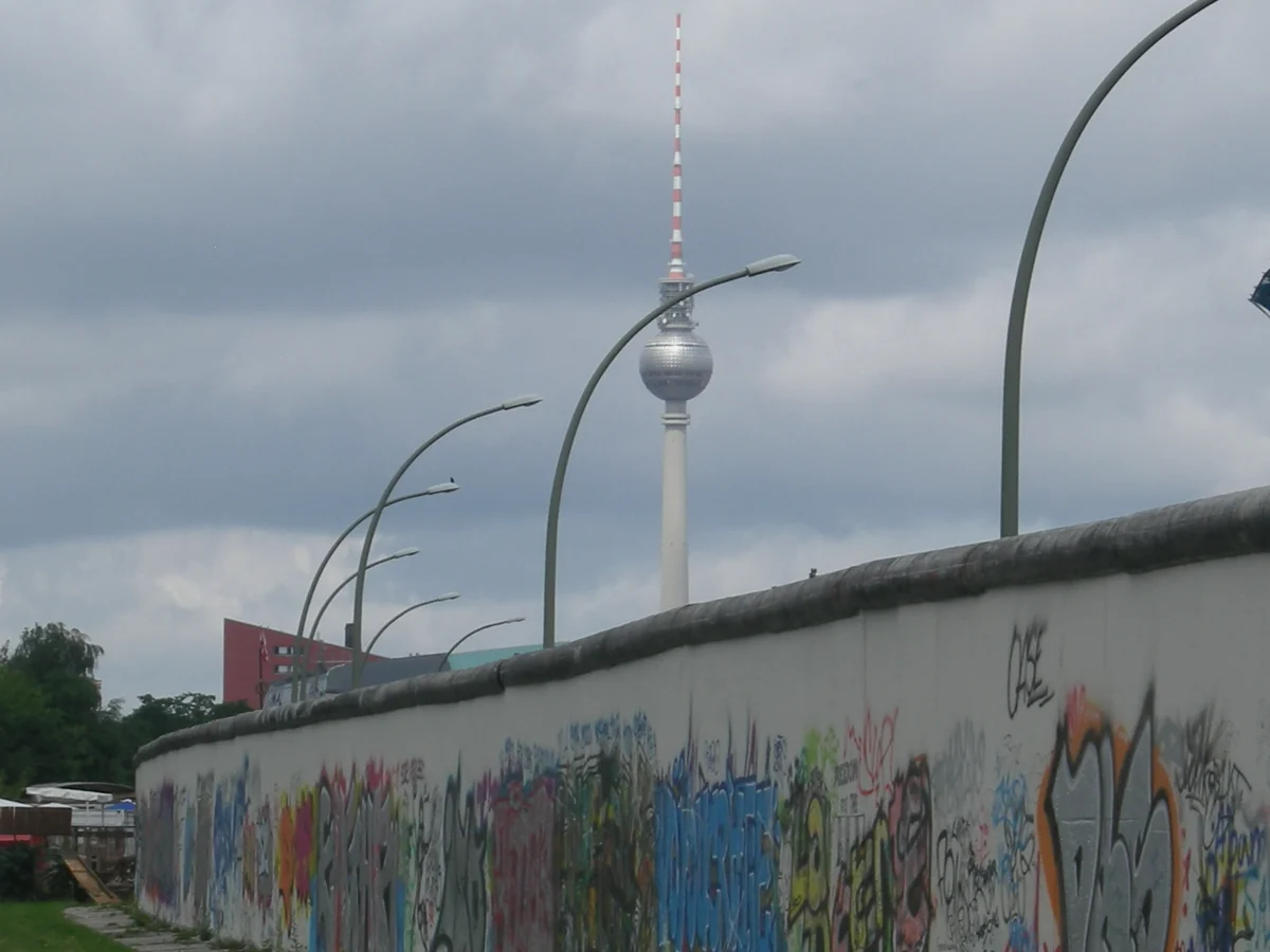 The Berliner Fernsehturm TV tower rises behind a graffiti-covered segment of the Berlin Wall at the East Side Gallery.